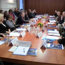 A group of people sitting around a table with a large number of documents.